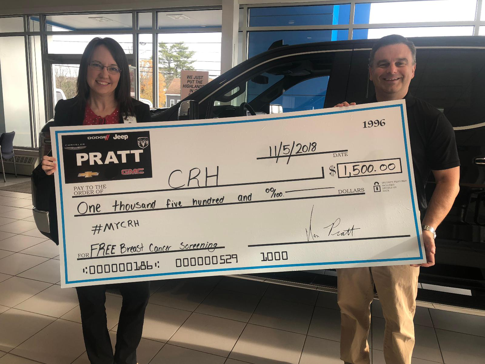 Two individuals proudly display a large check 