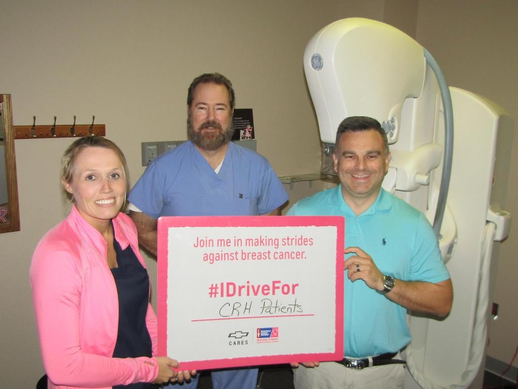 Three individuals proudly display a large check